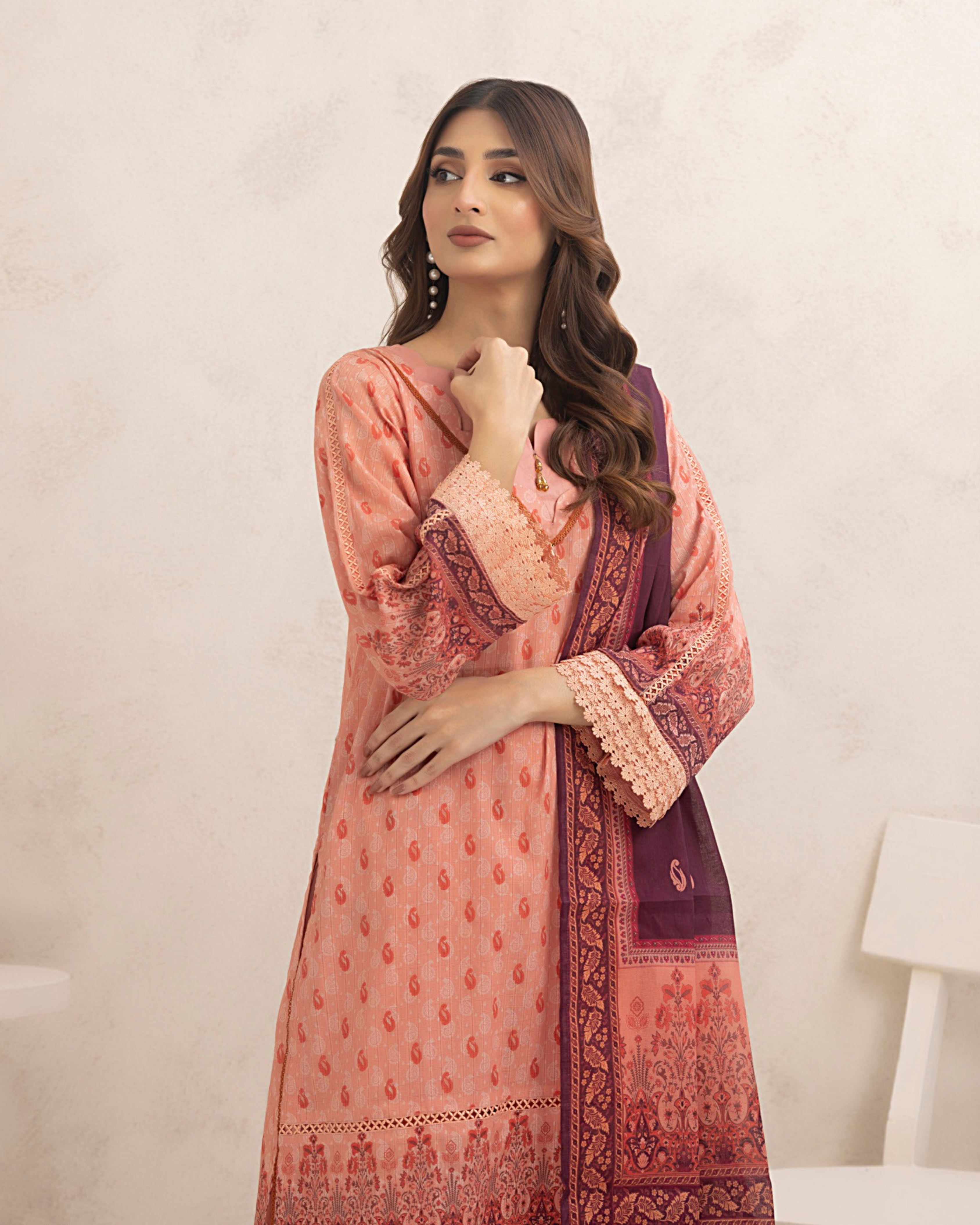 Woman wearing a pink and red embroidered traditional outfit on a plain background