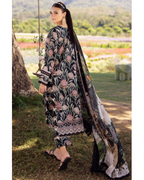 Woman in a floral embroidered outfit with a long scarf in an outdoor setting.