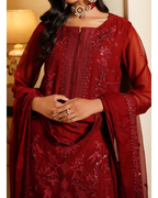 Red embroidered traditional outfit with matching dupatta, worn by a person indoors.