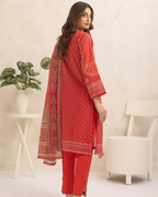Woman wearing a red traditional outfit with intricate patterns in a minimalistic room.