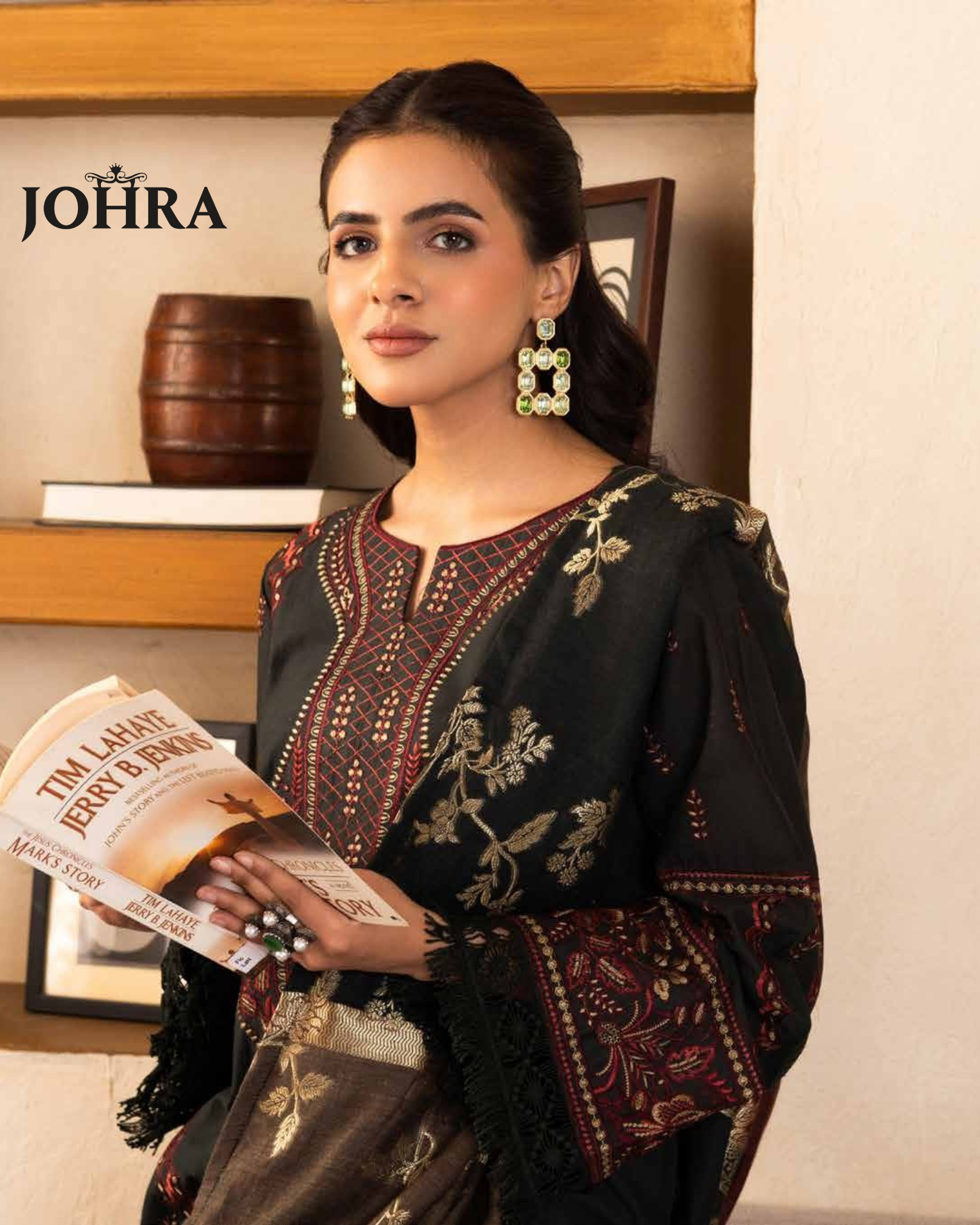 Woman in traditional attire holding a book with 'JOHRA' branding in the background