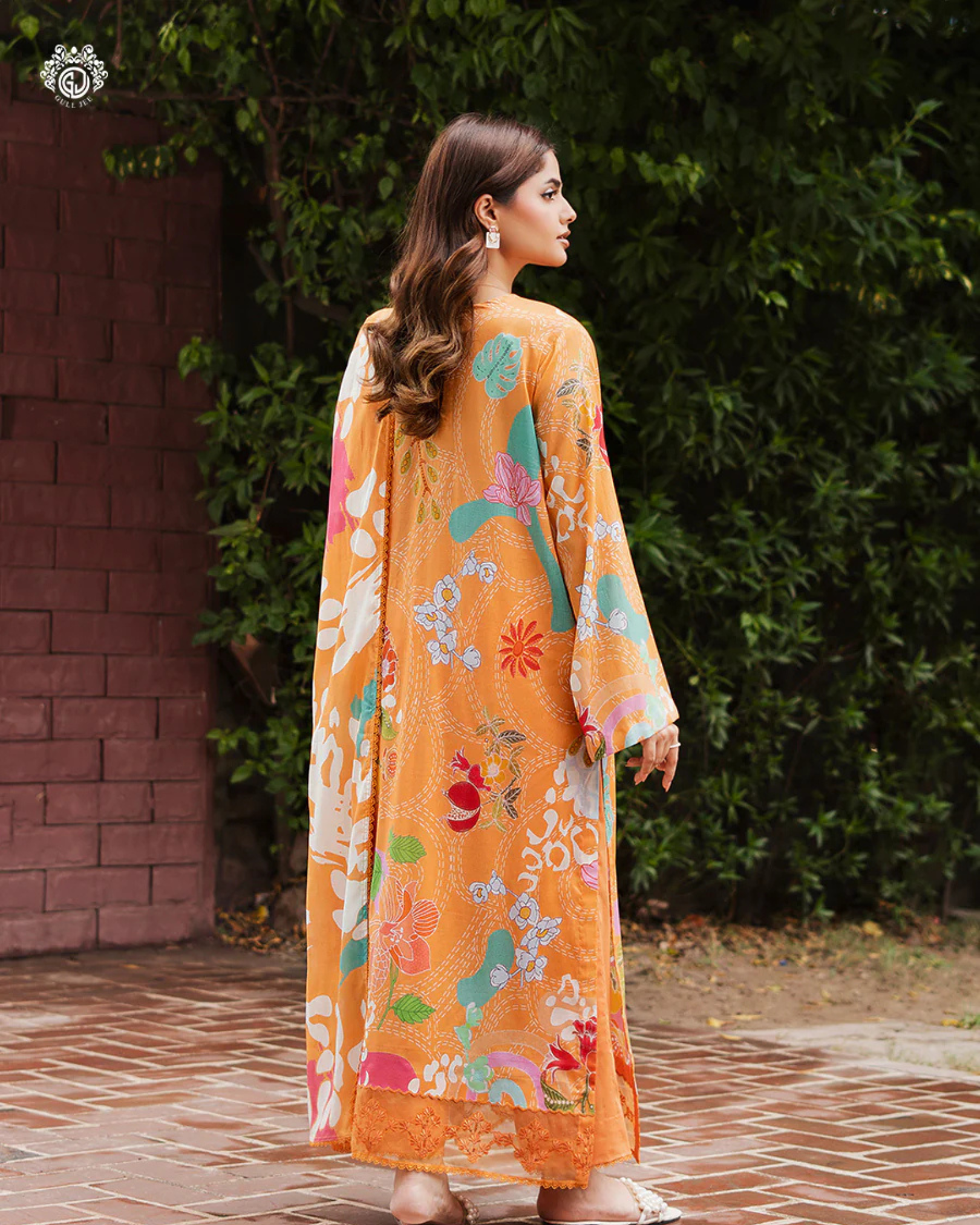 Woman wearing a floral dress with a colorful dupatta, standing outdoors.