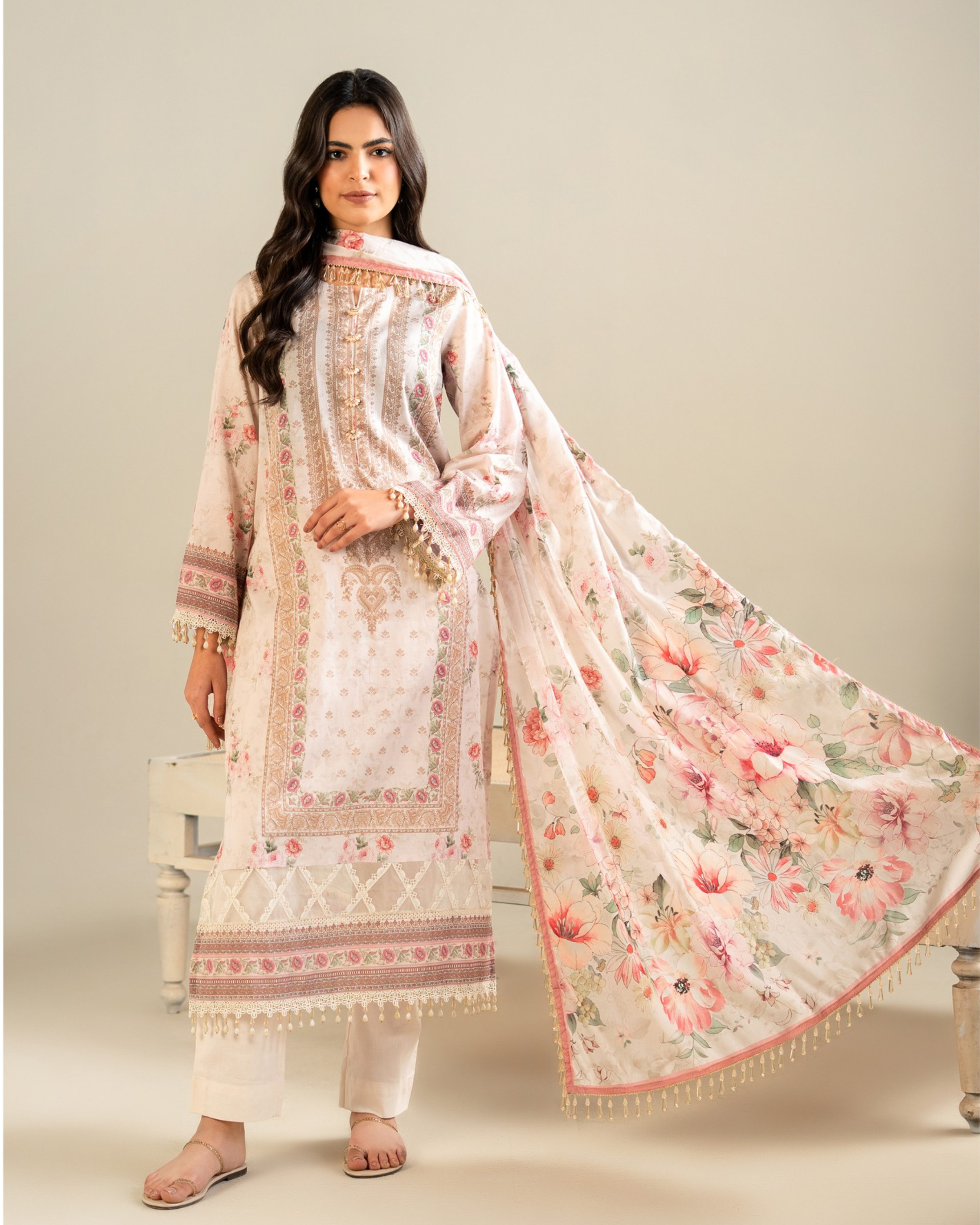 Woman wearing a floral embroidered outfit with a matching dupatta on a neutral background