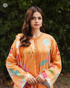 Woman wearing an orange floral dress against a green leafy background