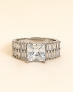 Ring with a large central gemstone and smaller stones on a beige background