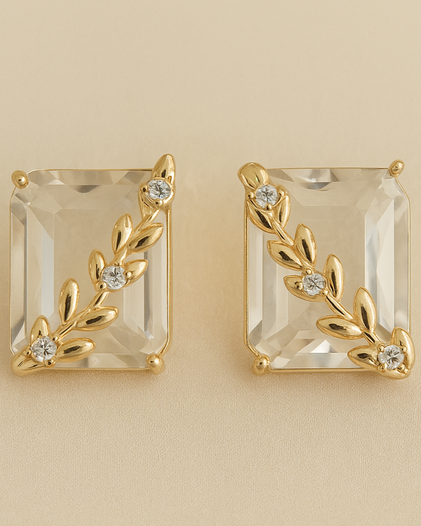 Gold earrings with clear gemstones on a beige background