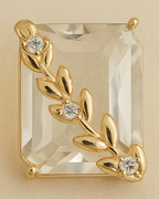 Gold earrings with clear gemstones on a beige background