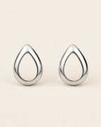Pair of silver teardrop-shaped earrings on a beige background
