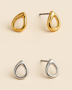 Gold and silver teardrop-shaped earrings on a beige background