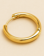 Gold hoop earrings on a beige background