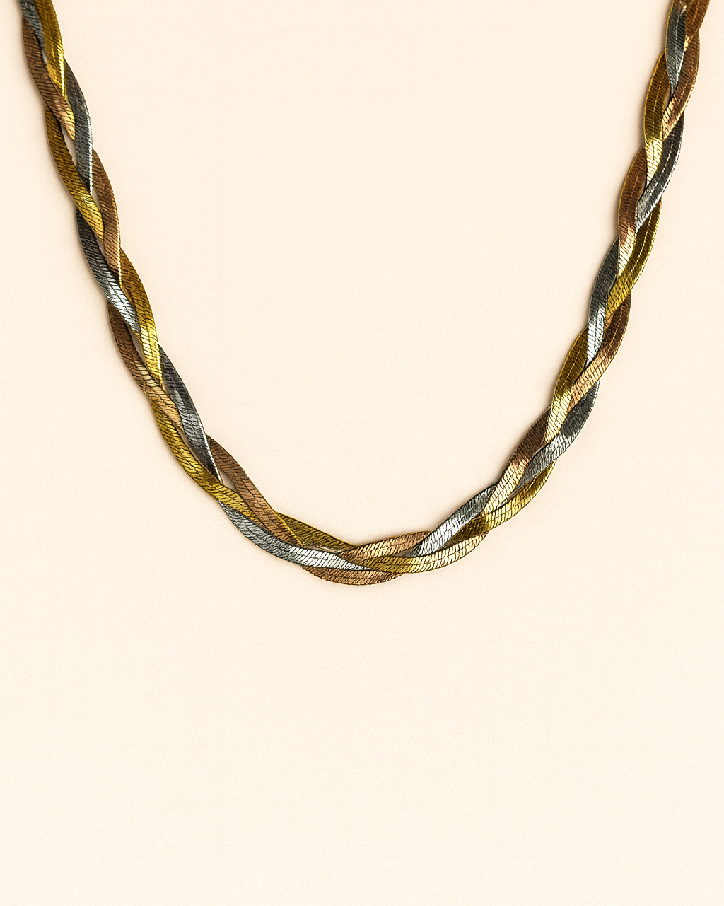 Braided necklace with gold, silver, and bronze tones on a beige background