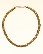 Braided necklace with gold and silver tones on a white background
